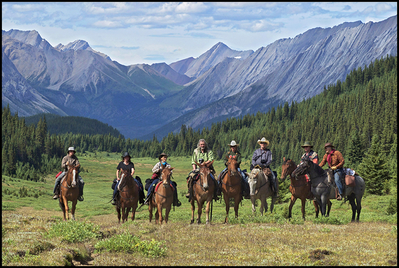 Group shot of Banff photography workshop participants on horseback with mountains in the background
